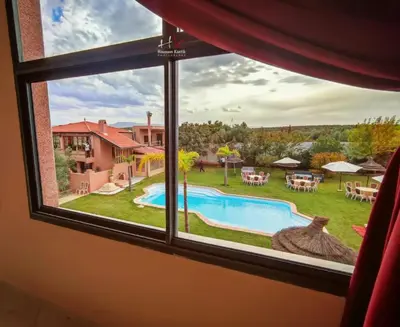 a window view of a swimming pool and a yard at Tynass Ferme - Atlas Room Fes