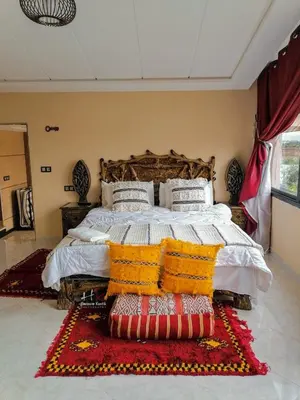 a bedroom with a large bed with blankets and pillows at Tynass Ferme - Atlas Room Fes