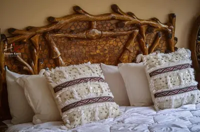 a bed with white pillows and a wooden headboard at Tynass Ferme - Atlas Room Fes
