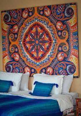 a painting on the wall above a bed with pillows at Tynass Ferme - Chefchaouen Room - Fes