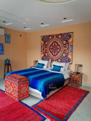 a bedroom with a bed with a large tapestry on the wall at Tynass Ferme - Chefchaouen Room - Fes
