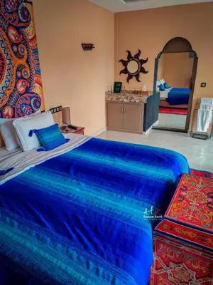 a bedroom with a large blue bed with a mirror at Tynass Ferme - Chefchaouen Room - Fes