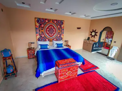 a bedroom with a blue bed with a red rug at Tynass Ferme - Chefchaouen Room - Fes