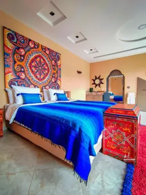 a bedroom with a large bed with a large tapestry at Tynass Ferme - Chefchaouen Room - Fes