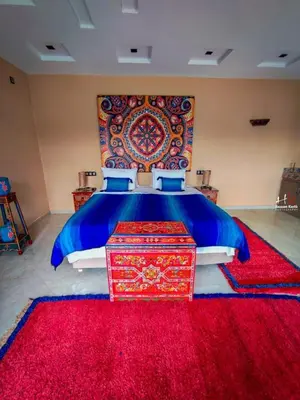 a bedroom with a large bed with a red rug at Tynass Ferme - Chefchaouen Room - Fes