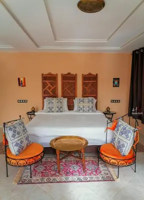 a bedroom with a large bed with orange chairs at Tynass Ferme - Fez Room Fes