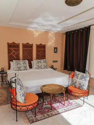 a bedroom with a bed with two chairs and a table at Tynass Ferme - Fez Room Fes