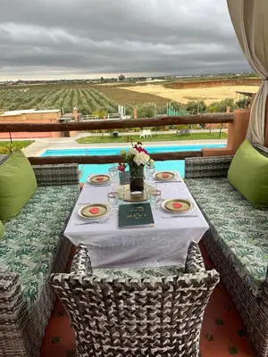 a table with a white table cloth and flowers on it at Ferme Tynass - Amazigh Room Fes