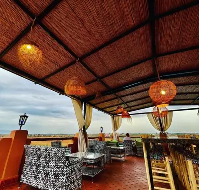 a patio with tables and chairs on a roof at Ferme Tynass - Amazigh Room Fes
