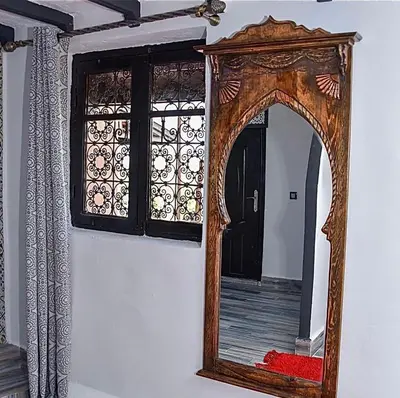 a mirror with a wooden frame on a wall at Ferme Tynass - Amazigh Room Fes