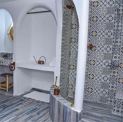 a bathroom with a shower and a tile wall at Ferme Tynass - Amazigh Room Fes