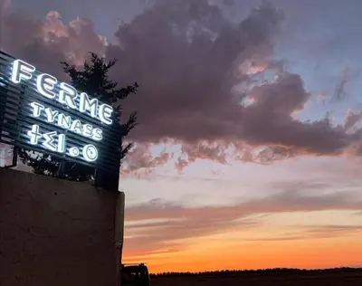 a sign for a restaurant with a sunset in the background at Ferme Tynass - Paris Room With Balcony Fes