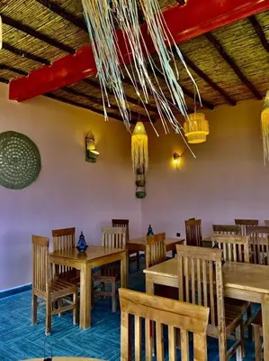 a restaurant with wooden tables and chairs and chandeliers at Ferme Tynass - Paris Room With Balcony Fes