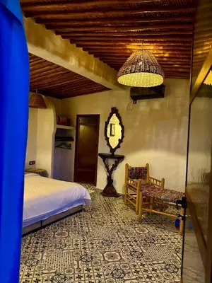 a bedroom with a bed and a chair and a lamp at Tynass Ferme - Walili Room Fez