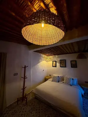 a bedroom with a large bed and a chandelier at Tynass Ferme - Walili Room Fez