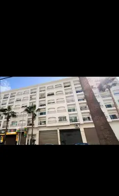 a large white building with palm trees in front of it at Mandela in Oulad Akkou