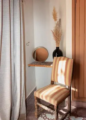 a chair in a room with a mirror and a shelf at Atlas Aura Hotel Ourika - Marrakech