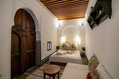 a bedroom with a bed and a large wooden door at Dar Rass Jnane in Fès