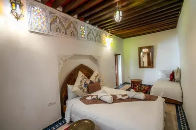 a bedroom with two beds with white sheets and a window at Dar Rass Jnane in Fès