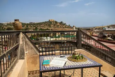 a table on top of a balcony with a book at Dar Rass Jnane in Fès