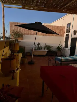 a patio with an umbrella and potted plants at Rooftop del quinto in Oulad Akkou