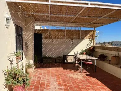 an outdoor patio with a table and a roof at Rooftop del quinto in Oulad Akkou