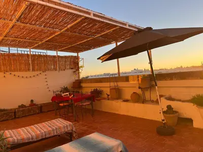 a patio with a table and an umbrella on a roof at Rooftop del quinto in Oulad Akkou