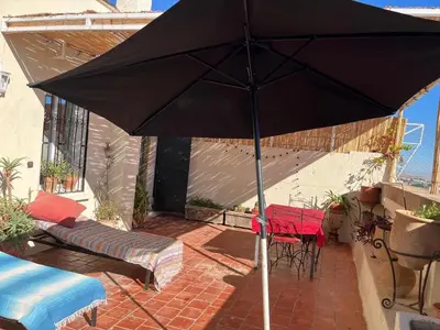 a black umbrella on a patio with a table and chairs at Rooftop del quinto in Oulad Akkou