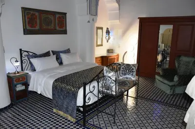 a bedroom with a large bed and a chair at Chambre SAPHIR - Riad Lotus Bleu in Fès