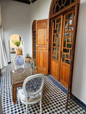 a room with a table and chairs and a door at Chambre SAPHIR - Riad Lotus Bleu in Fès