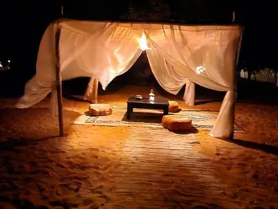 a tent with a table in the middle of a room at Merzouga Joy Camp in Hassilabied