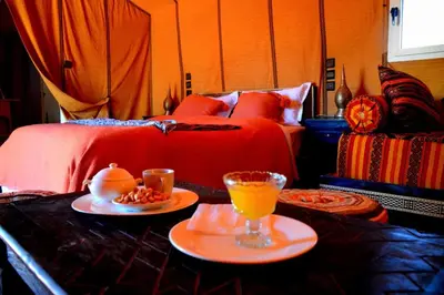 a bedroom with a bed and two plates of food on a table at Golden dunes luxury camp in Merzouga