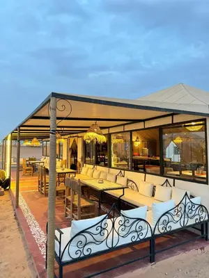 a pavilion with tables and couches on a patio at Golden dunes luxury camp in Merzouga