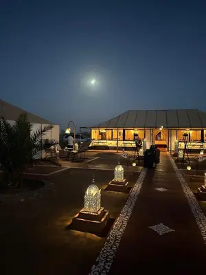 a large building with lights in front of it at night at Golden dunes luxury camp in Merzouga