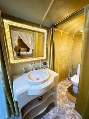 a bathroom with a sink and a mirror and a toilet at Golden dunes luxury camp in Merzouga