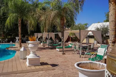 a pool with chairs and umbrellas next to a resort at Eden villa Marrakech in Douar bel Rhanodour