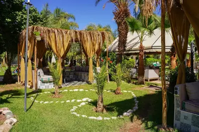 a garden with a gazebo and palm trees at Eden villa Marrakech in Douar bel Rhanodour