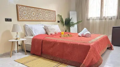 a bedroom with a bed with a red comforter at Appartement style traditionnel climatisé chaufé in Fès