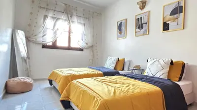 two beds in a room with yellow and blue sheets at Appartement style traditionnel climatisé chaufé in Fès