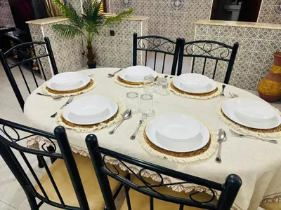 a table with white plates and napkins on it at Appartement style traditionnel climatisé chaufé in Fès