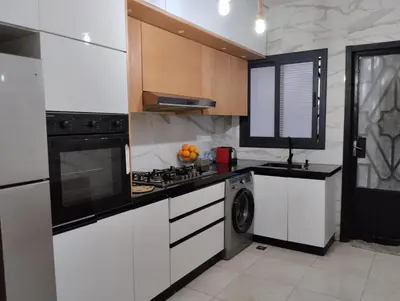 a kitchen with white cabinets and a stove top oven at Appartement style traditionnel climatisé chaufé in Fès