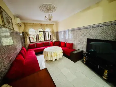 a living room with a red couch and a table at Appartement style traditionnel climatisé chaufé in Fès