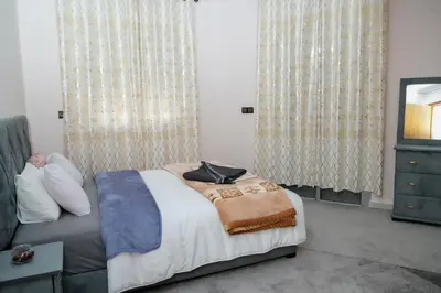 a bedroom with a bed and a dresser and curtains at Appartement Laaz in Midelt