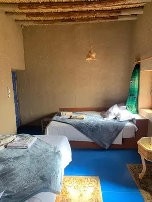 two beds in a room with blue floors at Kasbah Hôtel Rama in Merzouga