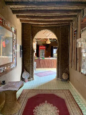 a hallway with an archway with a table and a rug at Kasbah Hôtel Rama in Merzouga