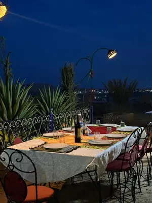 a table with plates and wine bottles on top of it at Kasbah Hôtel Rama in Merzouga