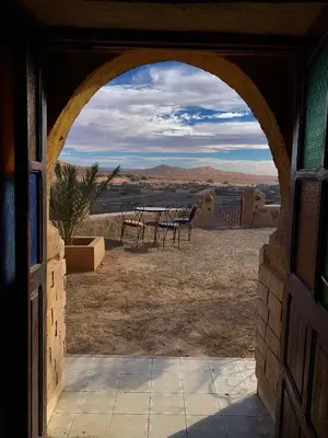 an open door to a patio with a table and chairs at Kasbah Hôtel Rama in Merzouga