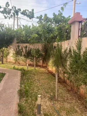 a garden with trees in the grass next to a wall at Atlas stay in Fès