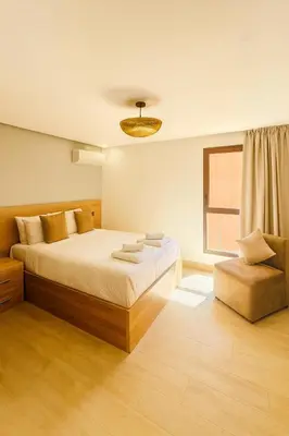 a bedroom with a large bed and a chair at Duplex 3 chambres - Piscine & Gym à 5 min du Carre Eden - Marrakech Center in Oulad Akkou