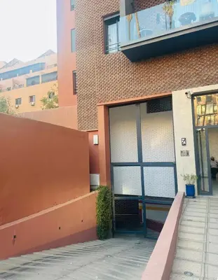 a building with a large garage door with a balcony at Duplex 3 chambres - Piscine & Gym à 5 min du Carre Eden - Marrakech Center in Oulad Akkou